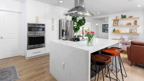 A modern kitchen with white cabinetry, stainless steel appliances, and a central island with stools. - Boca Family Fun & Charm - Villa Near Downtown & Beach (Boca Raton)