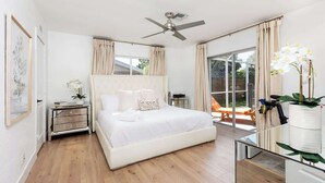 A bedroom with a bed, a nightstand, a ceiling fan, and a view of the outdoors. - Boca Family Fun & Charm - Villa Near Downtown & Beach (Boca Raton)