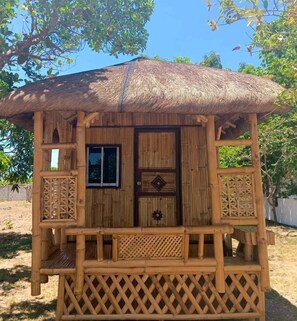 A small wooden structure with a thatched roof, a window, and a door with a decorative emblem. - Maxbelle Mountain Resort (Daanbantayan)