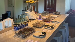 A long dining table with various dishes, glasses, and a vase of flowers. - Maxbelle Mountain Resort (Daanbantayan)