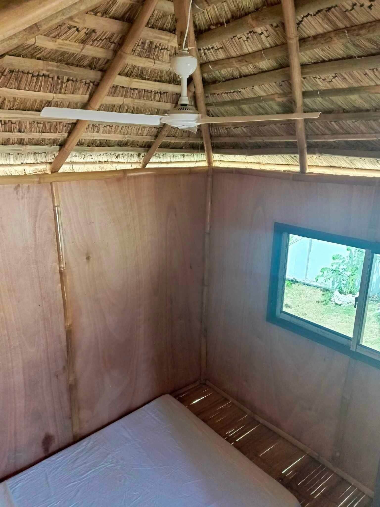 Una habitación con techo de madera, ventilador de techo, ventana y cama.