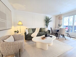 A modern living room with a sofa, coffee table, and dining area. - 2 Bedroom Suite Downtown w/ Parking (Edmonton)