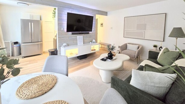 Ein modernes Wohnzimmer mit Flachbildfernseher, einer weißen Unterhaltungsanlage und einem Sofa.