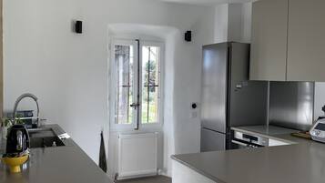 Une cuisine moderne avec des meubles blancs, un réfrigérateur en acier inoxydable et un four encastré.