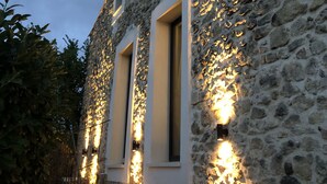 Un bâtiment en pierre doté de deux fenêtres, chacune étant éclairée par des lampes fixées au mur.