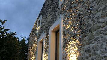 Un bâtiment en pierre doté de deux fenêtres, chacune étant éclairée par des lampes fixées au mur.