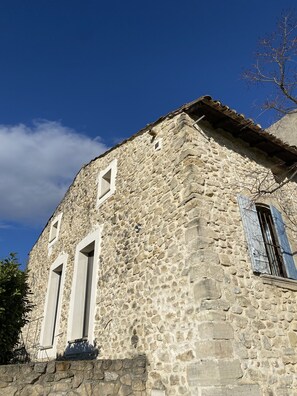 A stone building with a sloped roof and two windows with shutters. - Ancien Moulin en Pierre (Saint-Pierre-de-Vassols)