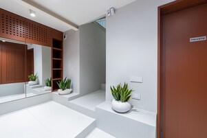 Un bagno moderno con uno specchio grande, un piano di lavoro bianco e piante in vaso.