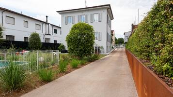 Una strada residenziale con case, un marciapiede e una recinzione in metallo.