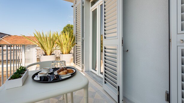 A balcony with a table set for two, featuring a tray with pastries and coffee. - Villa Fedora Luxury Suites (Lucca)