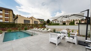 A rooftop pool area with a swimming pool, lounge chairs, and outdoor furniture. - Villa Fedora Luxury Suites (Lucca)