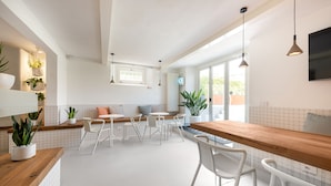 A modern kitchen with white cabinetry, a wooden countertop, and a seating area with white chairs and a round table. - Villa Fedora Luxury Suites (Lucca)