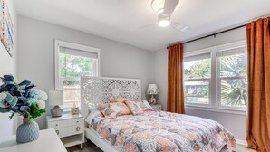 A bedroom with a bed, white nightstands, a white dresser, a vase with flowers, and a window with curtains. - Idyllic Sarasota Home w/ Yard: 2 Mi to Beach! (Sarasota)