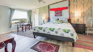 A bedroom with a bed, a desk, and a chair, a balcony with a view, and a ceiling fan. - Dreamy Home on Lake Istokpoga w/ Dock + Views! (Lake Placid)