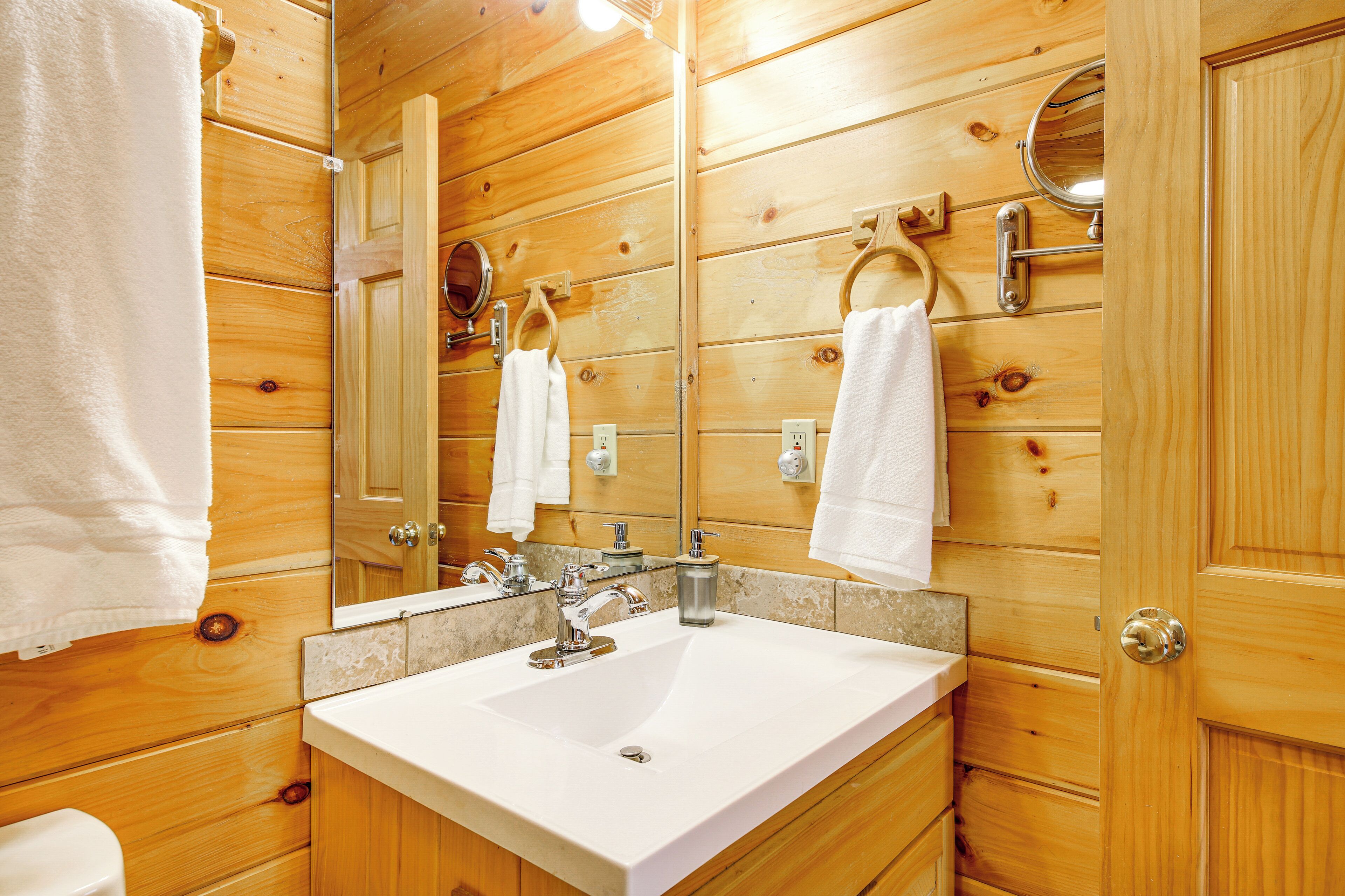Une salle de bain en bois avec un lavabo blanc, un miroir et deux porte-serviettes.