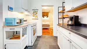 A compact kitchen with white cabinetry, a blue microwave, and a coffee maker. - Lovely Mobile Home w/ Smart TV: 2 Mi to Downtown! (Mobile)