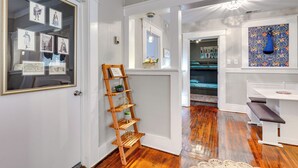 A hallway with a wooden ladder shelf, framed artwork, and a blue hanging ornament. - Lovely Mobile Home w/ Smart TV: 2 Mi to Downtown! (Mobile)
