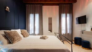 A bedroom with a large bed, a TV, and a window with curtains.