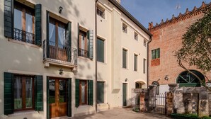 A traditional European building with a courtyard, featuring a brick wall, a gate, and a small garden area.