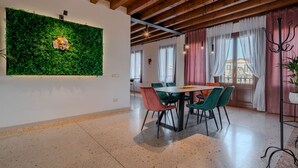 A dining area with a table and chairs, a green wall with a plant, and a window with curtains.