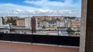 Un balcon offrant une vue sur le paysage urbain, avec différents bâtiments et un ciel dégagé.