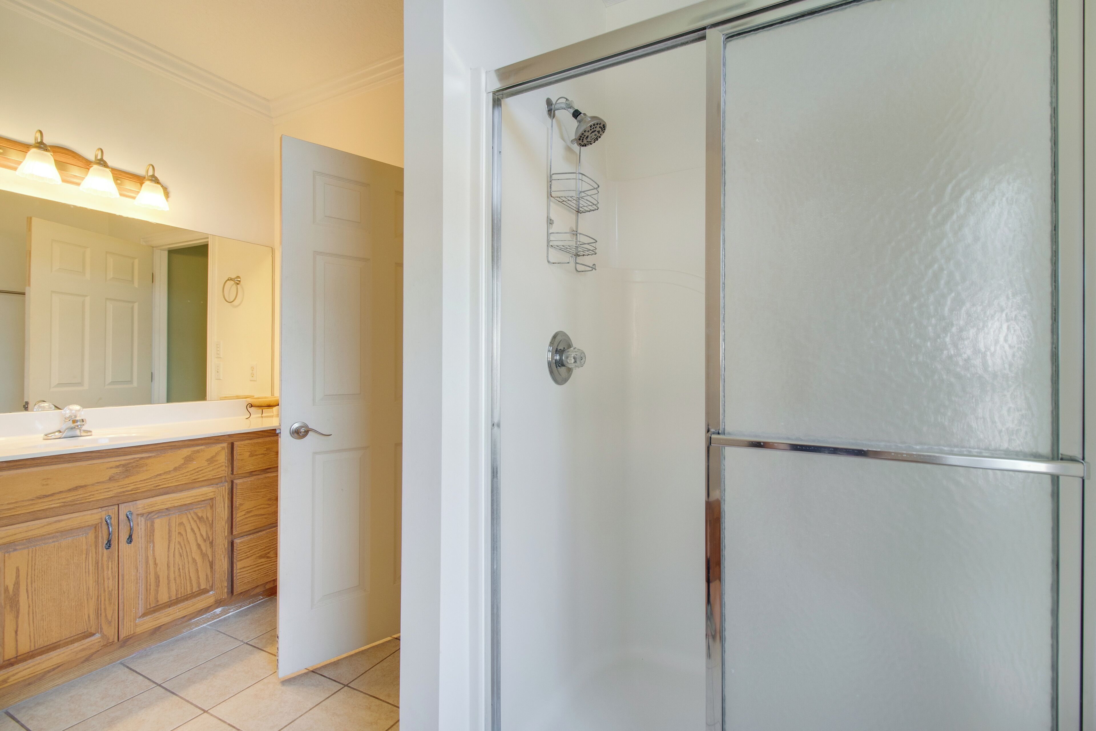 A bathroom with a wooden vanity, a mirror, and a shower enclosure.