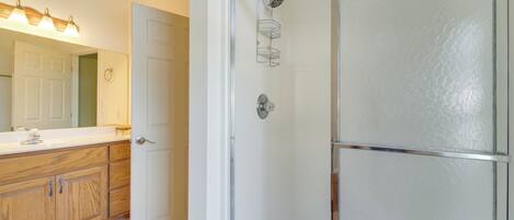 A bathroom with a wooden vanity, a mirror, and a shower enclosure.