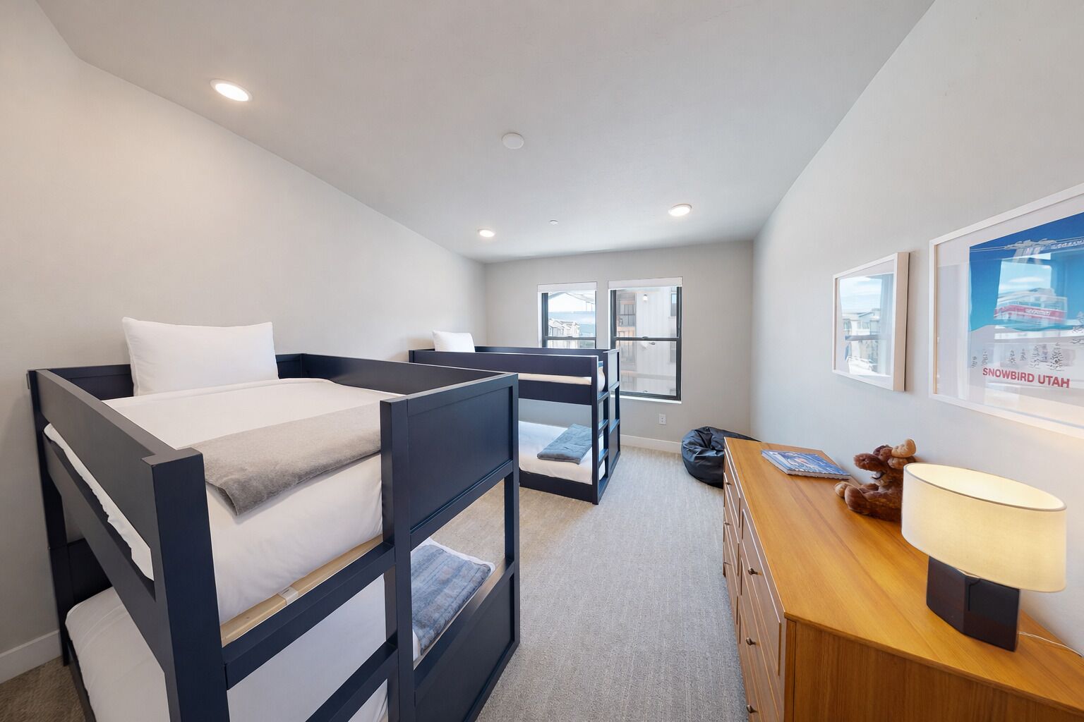 A modern bedroom with bunk beds, a desk, and a lamp.
