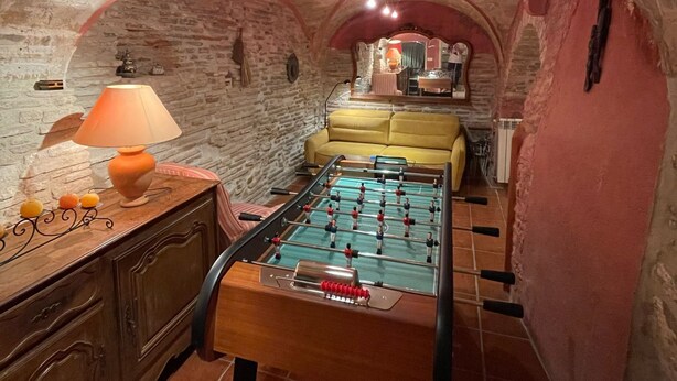 Una habitación acogedora con una mesa de fútbol de mesa, un sofá y una lámpara.