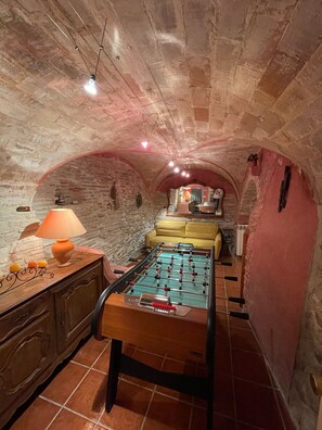 A cozy room with a foosball table, a sofa, and a lamp.