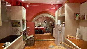 Una cocina con pared roja, arco de piedra y suelo de baldosas.