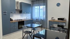 Une cuisine compacte avec un coin repas, équipée d’une cuisinière, d’un four à micro-ondes et d’appareils électroménagers modernes.
