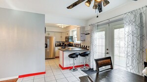 A modern kitchen with a central island, bar stools, and a dining table with chairs.