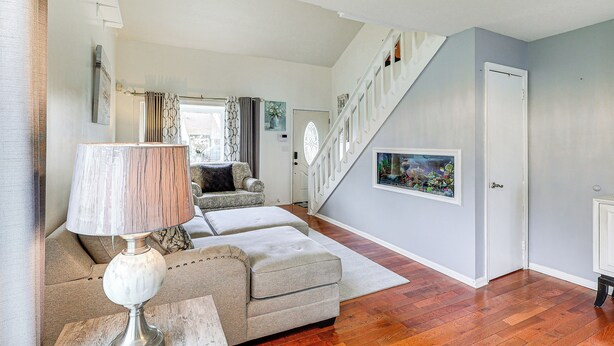 A living room with a sofa, a lamp, a staircase, and a door.