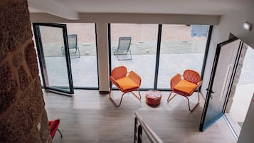 A spacious balcony with two wicker chairs and a round ottoman, overlooking a paved area.