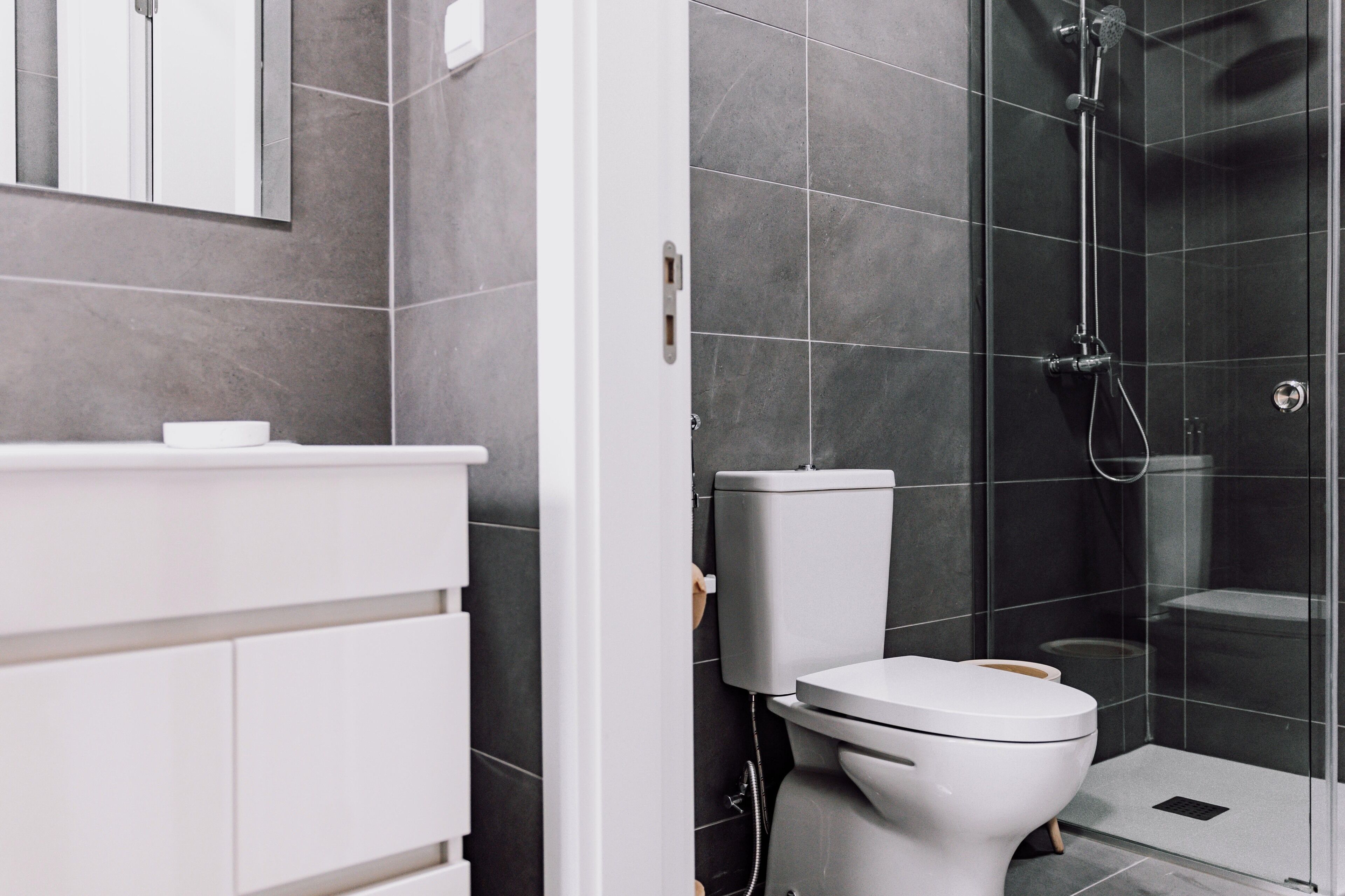 A modern bathroom with a white toilet, a glass shower enclosure, and a white vanity.