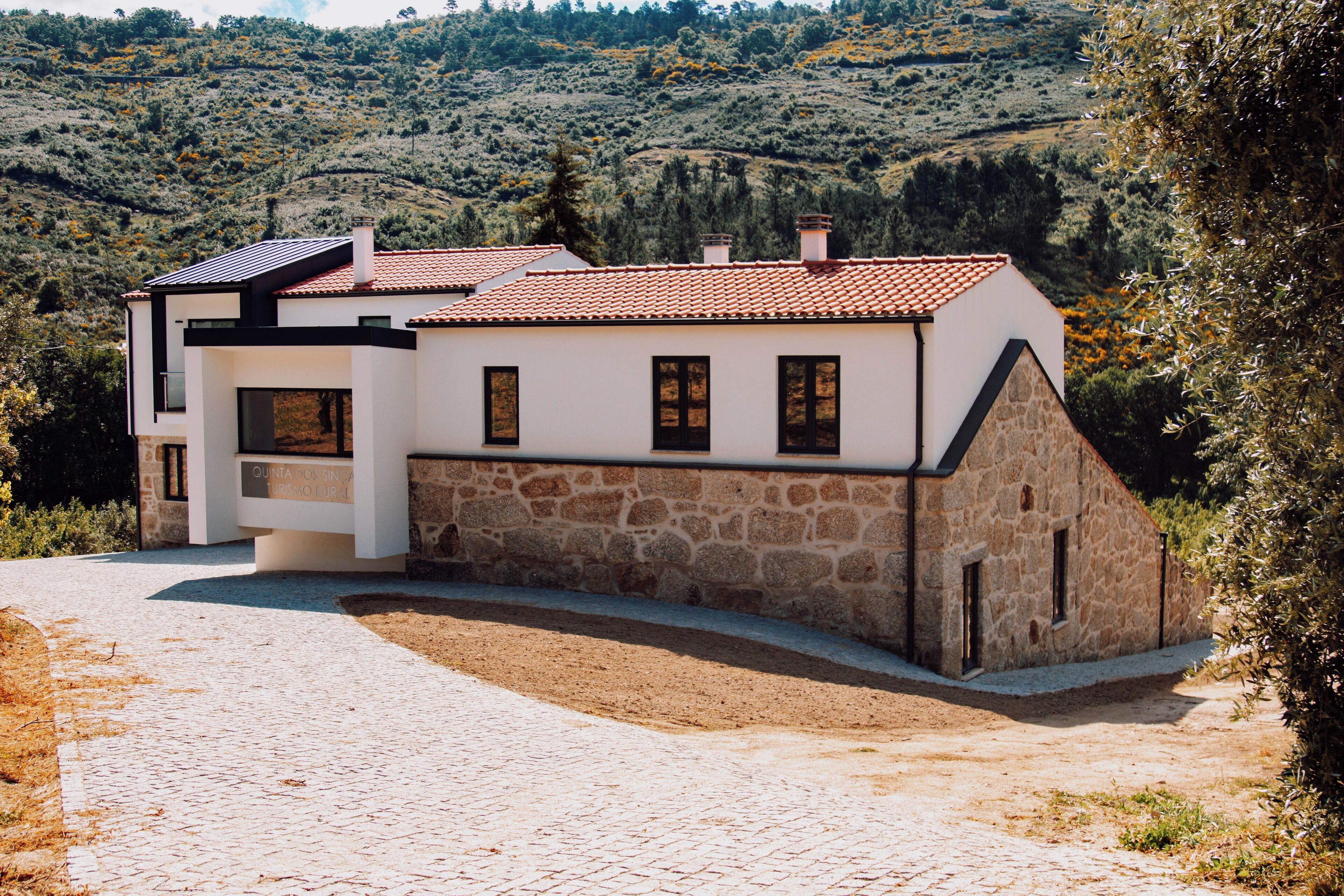Ein modernes Haus mit Naturstein-Fassade, Ziegeldach und befestigter Auffahrt.