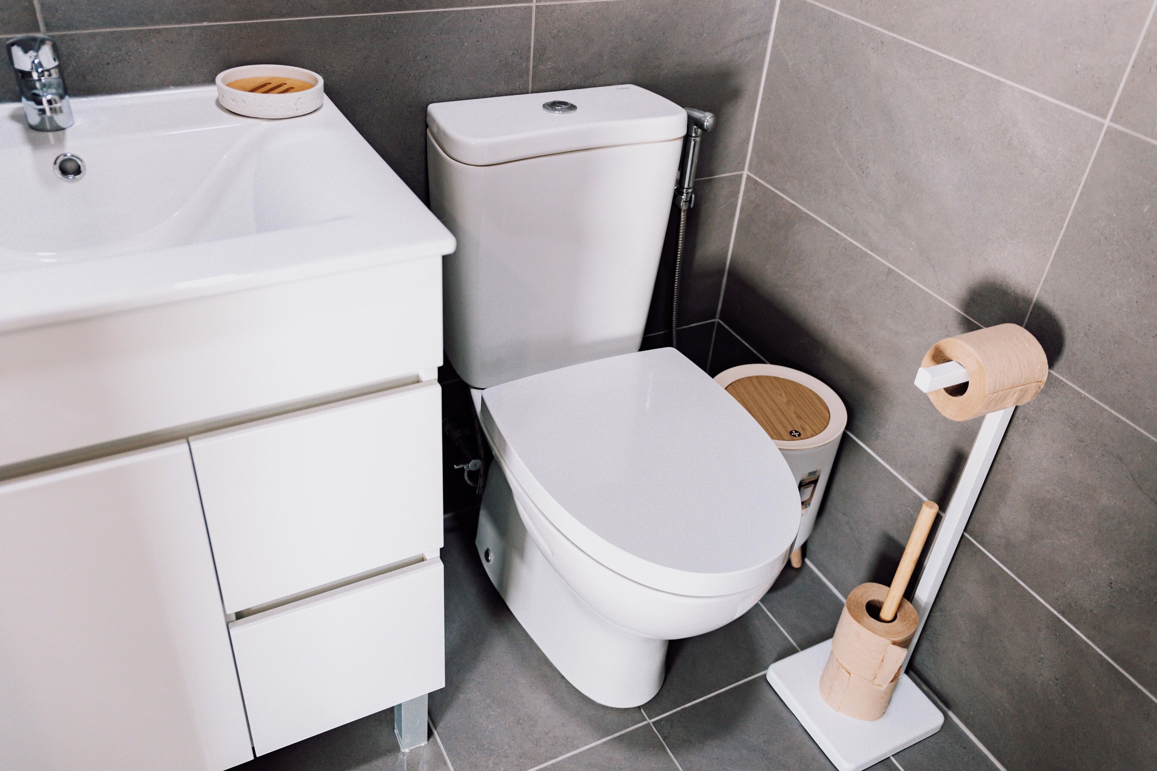 A modern bathroom with a white sink, toilet, and bidet.