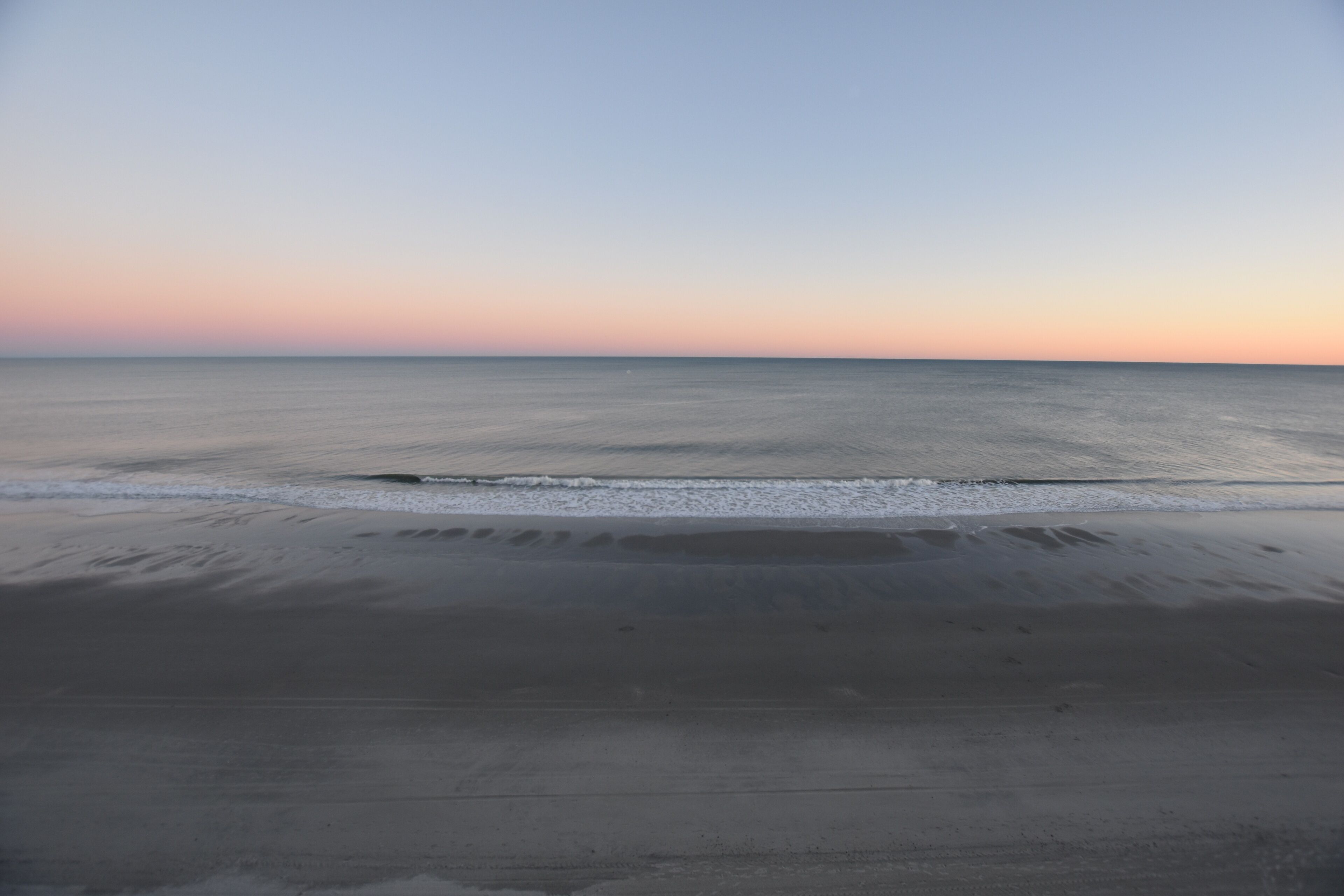 A beach with a calm sea and a clear sky.