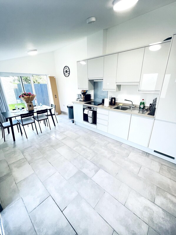 A modern kitchen with white cabinets, a dining area with a table and chairs, and a large window.