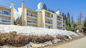 Un hôtel à plusieurs étages, doté de balcons et surplombant une pente enneigée.