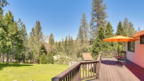 A wooden deck with a table and an umbrella, surrounded by a forest. - Cozy Cabin in Pine Mountain Lake Near Yosemite! (Groveland)