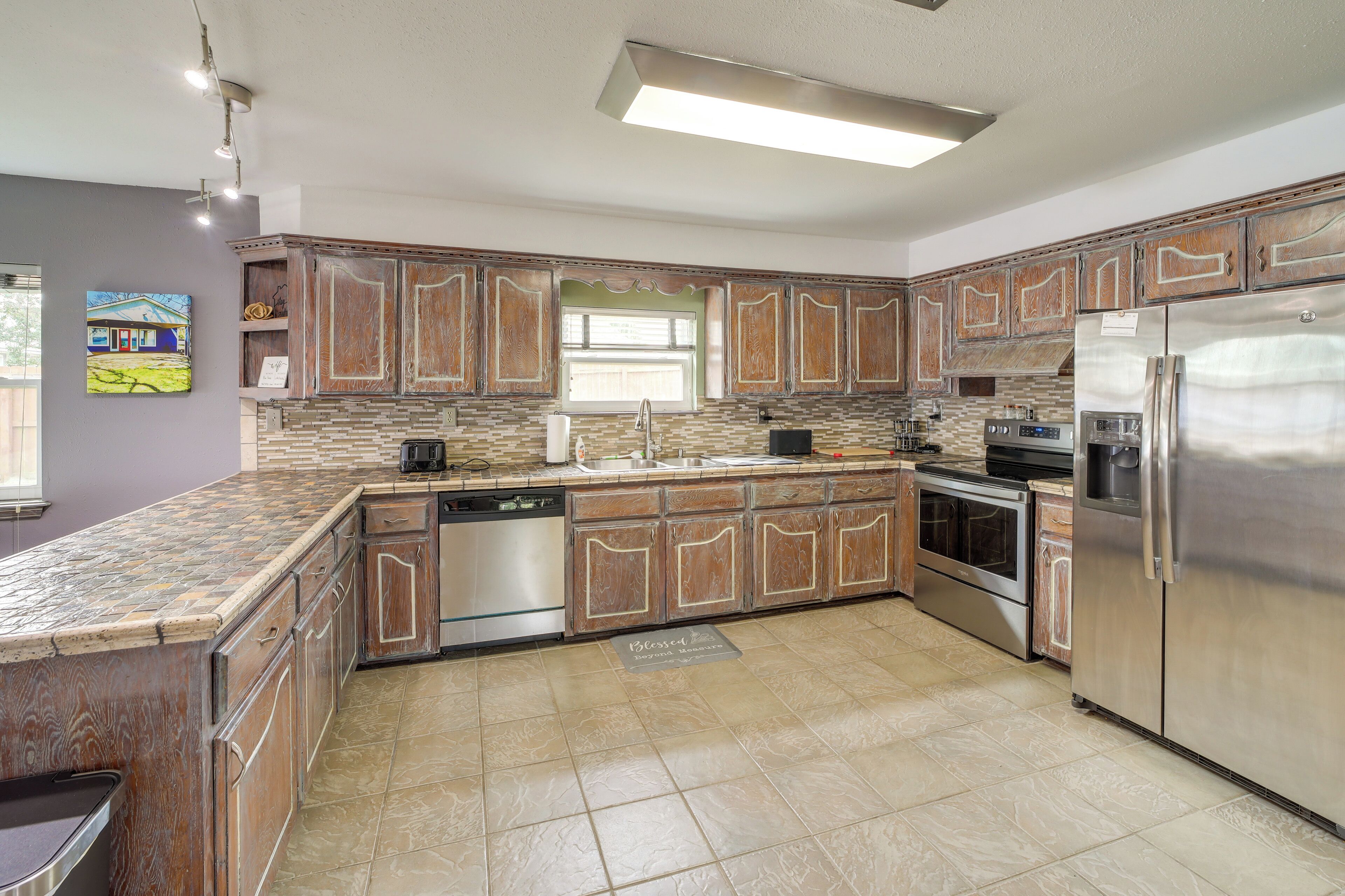 A modern kitchen with granite countertops, stainless steel appliances, and wooden cabinetry.