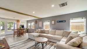 A spacious living room with a sectional sofa, a round coffee table, and a dining area with a table and chairs. - Lakefront Eufaula Cabin w/ Fire Pit & Private Dock (Eufaula)