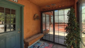 A wooden porch with a bench, a door labeled "Boot Room," and a Christmas tree. - Sunrise Pines Cabin | Spa · Near Village (Big Bear Lake)