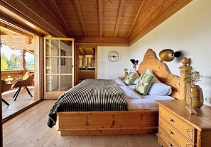 A wooden bedroom with a bed, dresser, and a large window. - Traumhaftes Luxus-Chalet für 8 Personen zwischen Kitzbühel & Ellma (Schattseite)
