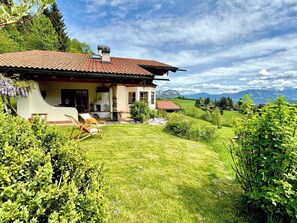 Ein Haus mit rotem Ziegeldach, einer kleinen Veranda und einem Rasen.