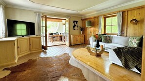 Een woonkamer met een houten vloer, een bank, een televisie en een groot bont tapijt.