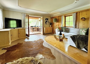 A living room with a wooden floor, a sofa, a television, and a large fur rug.