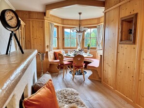 Ein Holzinterieur mit einem Esstisch, Stühlen, einer Uhr und einem Fenster mit Blick.